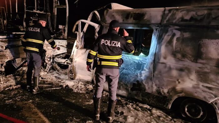 Polizeiermittler untersuchen das durch Feuer zerstörte Wrack des Krankenwagens.
