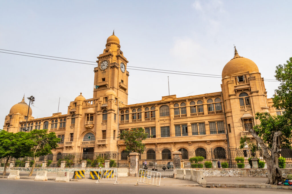 Größten Städte der Welt: Platz 16 Karachi: Karachi Municipal Corporation KMC-Gebäude Malerischer Blick auf die Jinnah Road mit regem Verkehr an einem bewölkten Tag