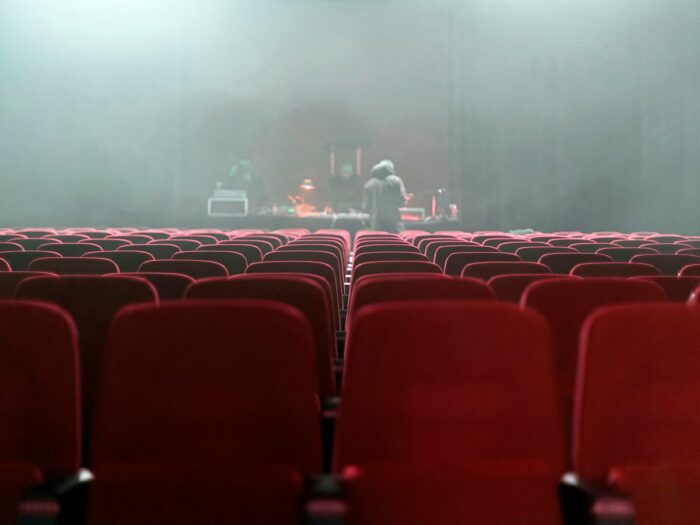 people sitting on red chairs watching a band performing on stage