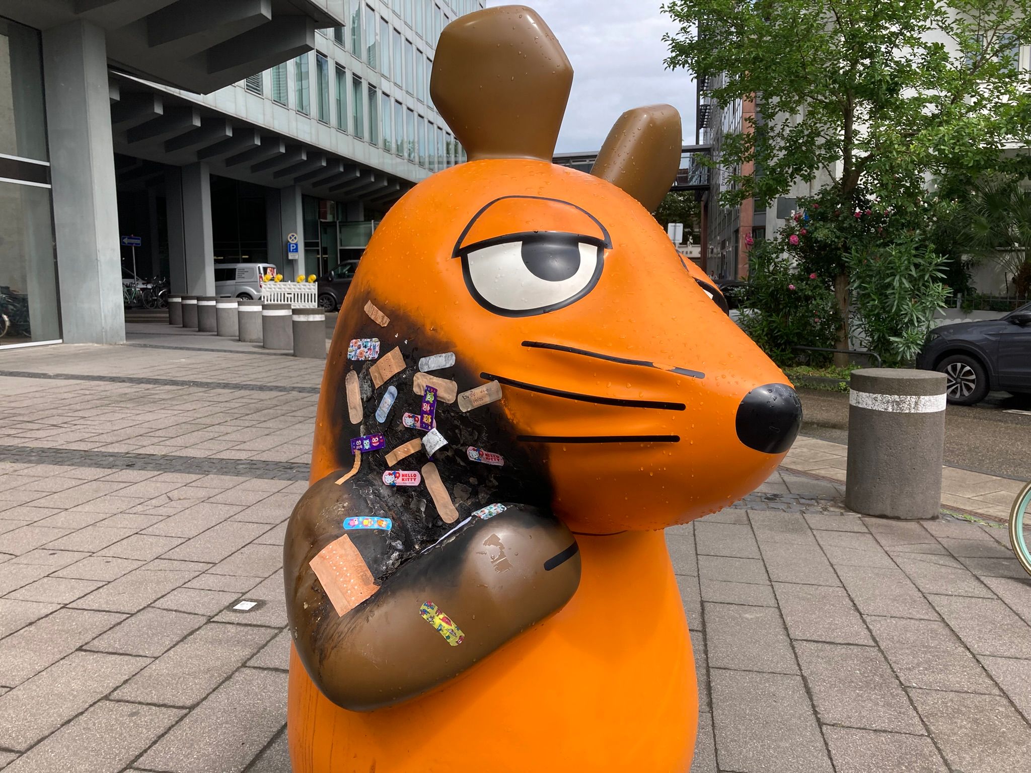 Angebrannte Maus-Figur wird mit Pflastern versorgt