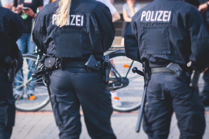 Zwei Polizeikräfte in dunkler Uniform mit Aufschrift POLIZEI, von hinten